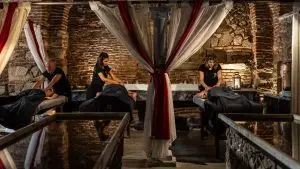 Espaço de luxo para massagens exclusivas, com massagistas profissionais num ambiente sofisticado, iluminado por velas e detalhes de água
