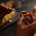 Una mano elegante extiende dulces artesanales sobre una tostada en un momento de indulgencia y placer sensorial en el spa In Acqua Veritas.